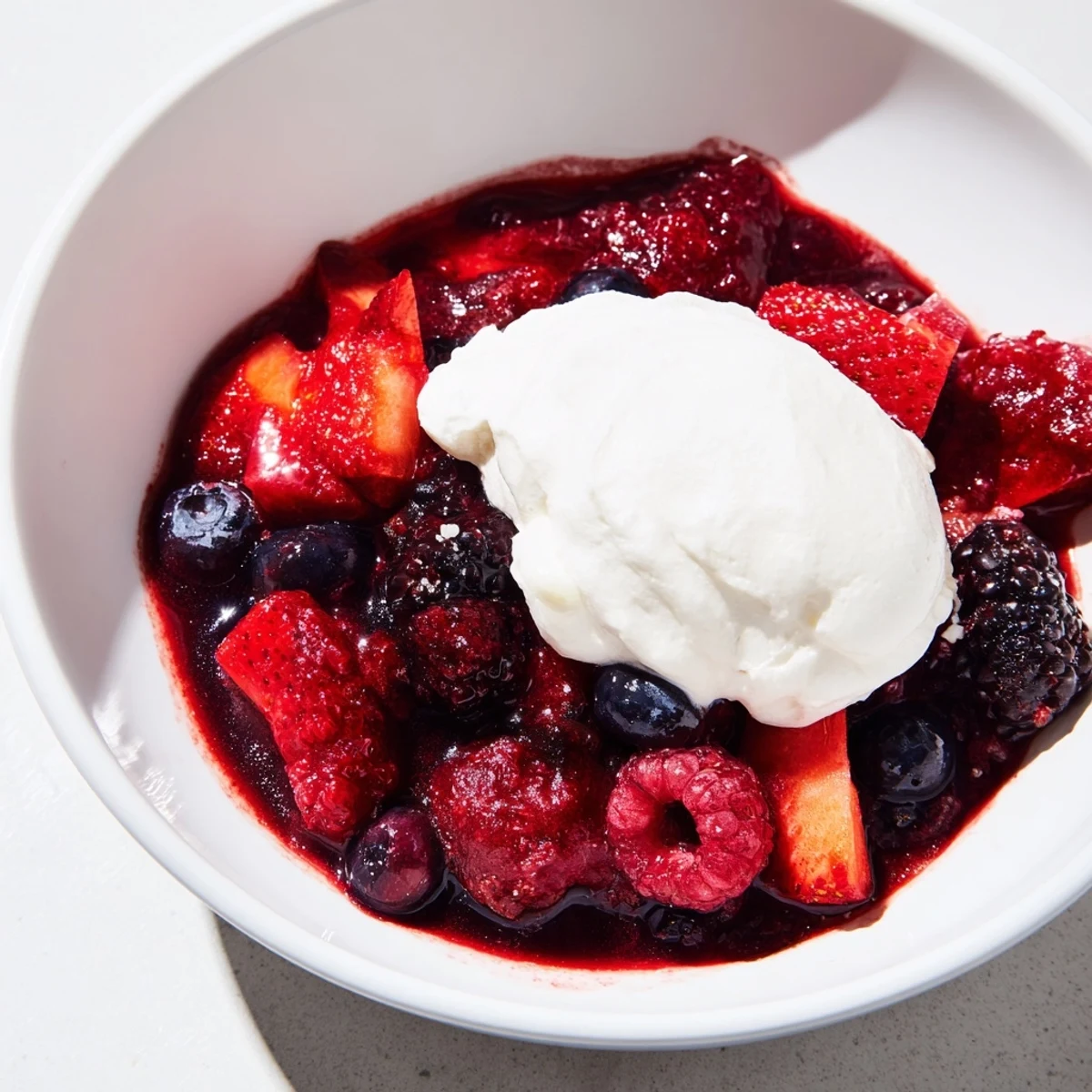 Vibrante Beerenkompott mit Sahne, perfekt als Dessert oder Topping.