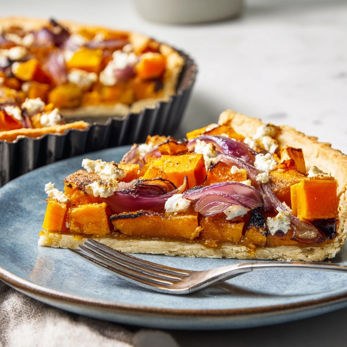 Close-up of a rustic Feuille d'Érable Tartes Salées d'Automne, highlighting caramelized onions and creamy goat cheese.