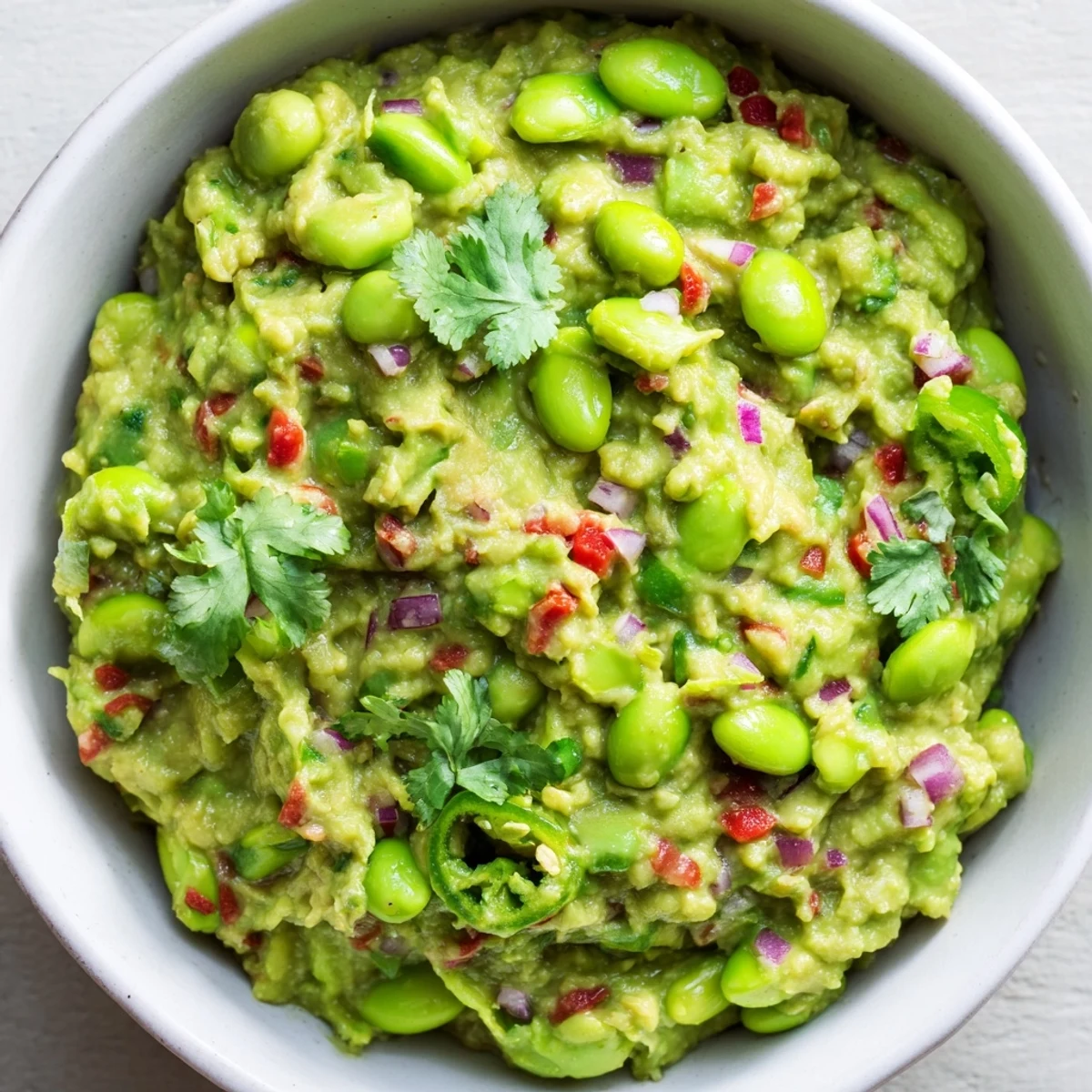 Creamy Edamame Guacamole, vibrant green, ready to be scooped with tortilla chips for a snack.