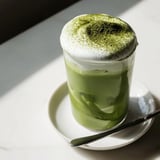 Frothy cold foam tops a bright green creamy matcha latte, perfect for a refreshing treat.