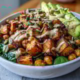 Crispy roasted chickpeas and caramelized sweet potatoes in a wholesome bowl with garlicky spinach and a drizzle of smoky chipotle tahini dressing.