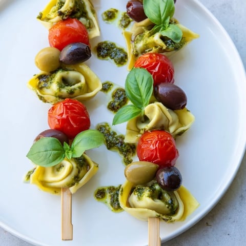 Appetizer Skewers: colorful tortellini, pesto, olives, and tomatoes are artfully arranged for serving.