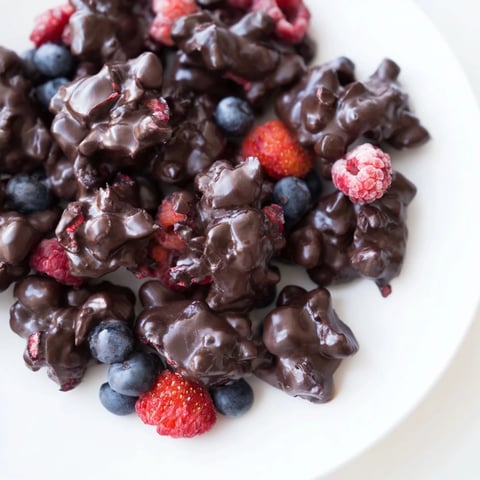 Frozen chocolate yogurt clusters, speckled with berries and glistening with dark chocolate coating.