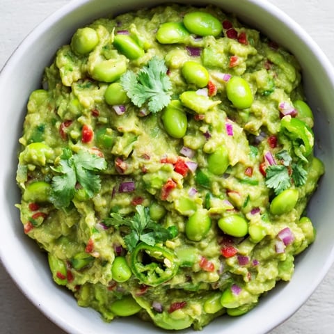 Creamy Edamame Guacamole, vibrant green, ready to be scooped with tortilla chips for a snack.