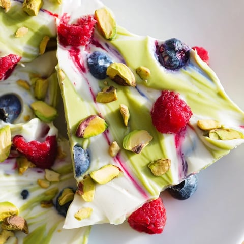 Frozen Yogurt Bark 3.0 swirled with vibrant matcha, berries, and pistachio cream, a delightful frozen treat.
