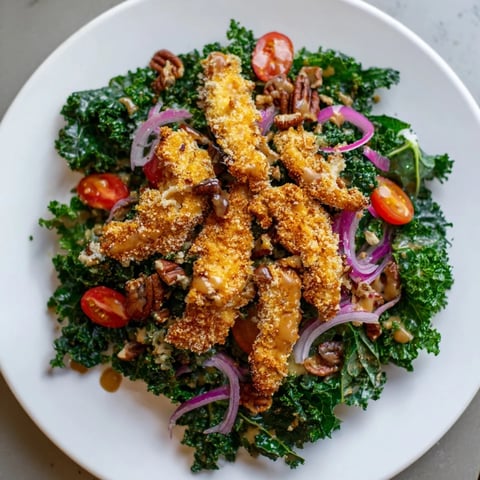 Ein goldenes, knuspriges Hähnchenstück liegt auf einer Schüssel mit frischem Grünkohl, Tomaten und roten Zwiebeln.