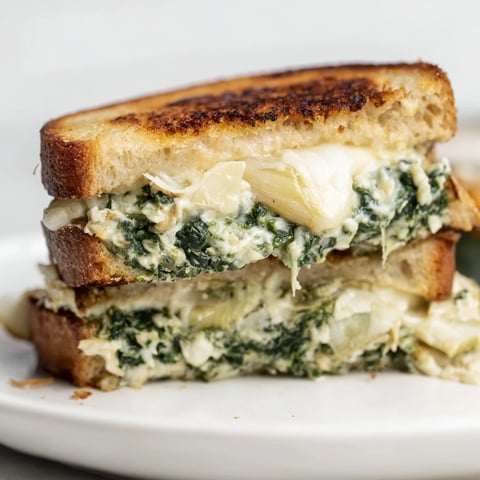 Golden-brown Artichoke Spinach Grilled Cheese with melted cheese and crispy sourdough crust.