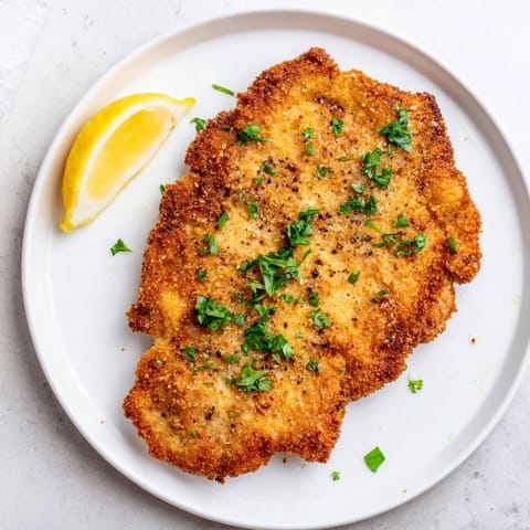 Crispy Air Fryer Wiener Schnitzel, perfectly cooked and breaded, awaits a squeeze of fresh lemon juice.