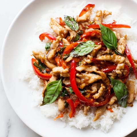 Aromatic, savory Thai Basil Chicken Bowls feature juicy chicken and fresh basil over fluffy rice, ready to eat.
