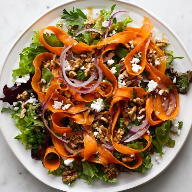 Knusprige geröstete Karottenstreifen auf Babyspinat und Rucola, angerichtet mit Honig-Senf-Dressing und gehackten Kräutern.