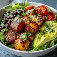 Colorful Sweet Potato and Black Bean Bowl with roasted veggies, creamy avocado, and zesty lime dressing.